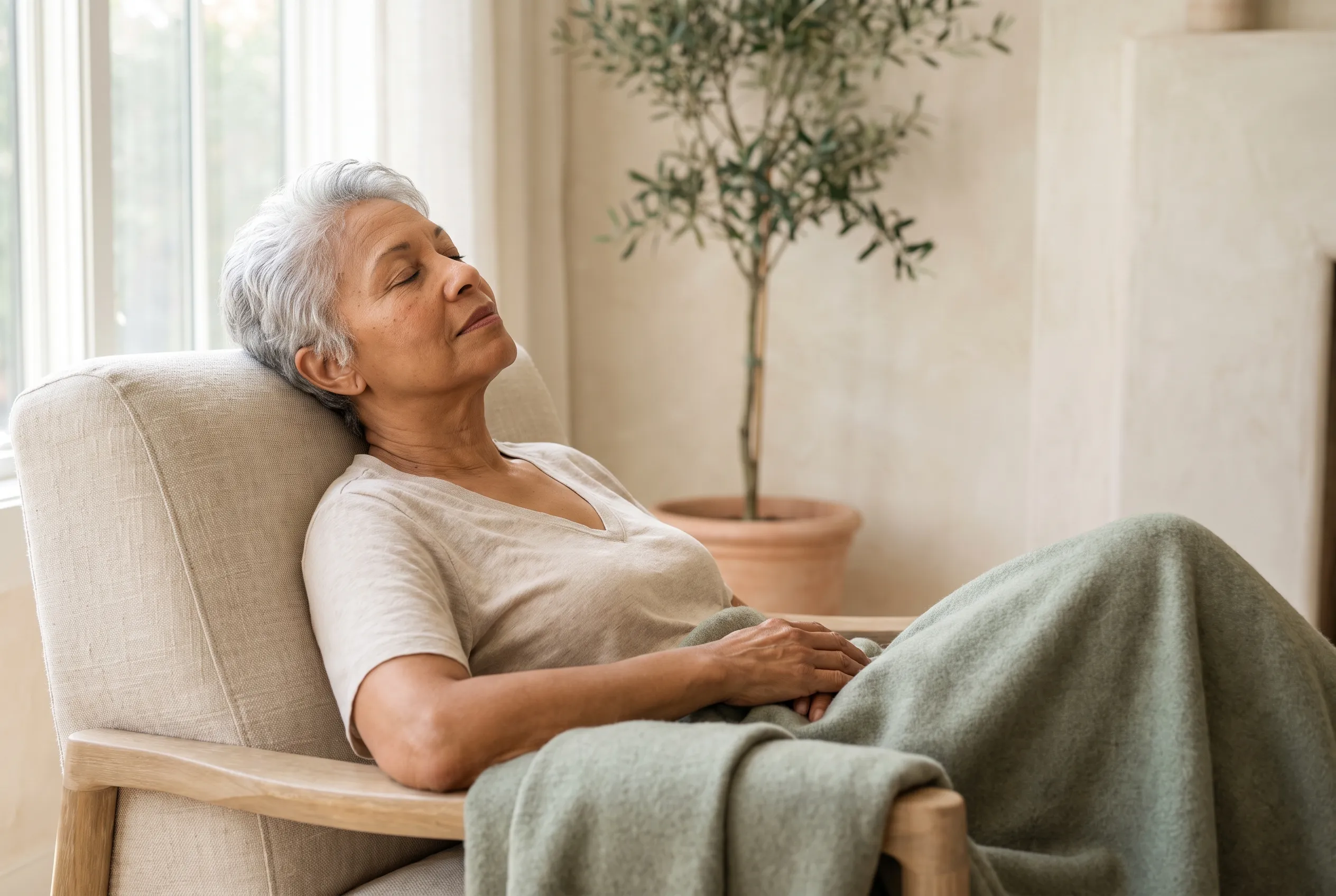 Woman resting comfortably in a linen chair with a sage blanket during a weight management session